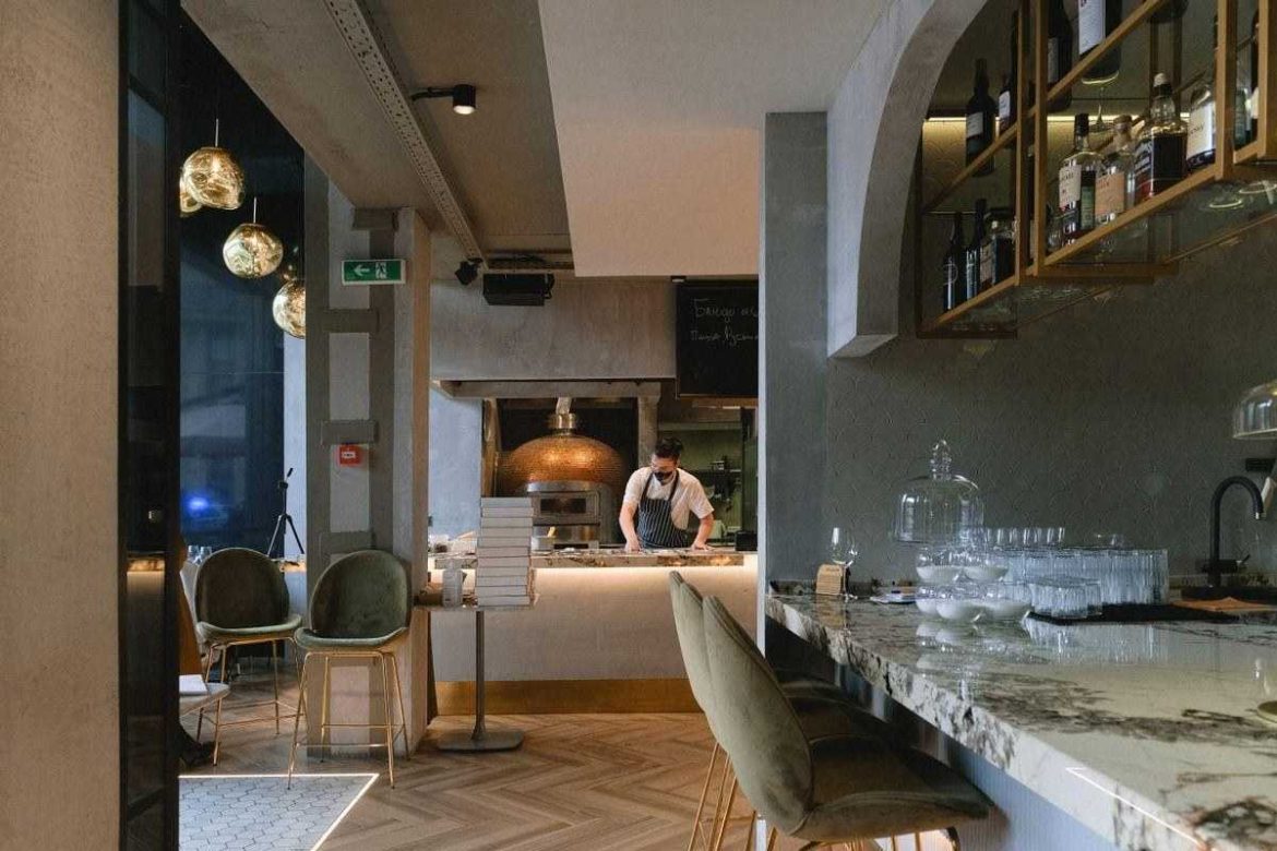 Exemple de décoration de restaurant moderne avec un comptoir en marbre, des chaises en velours vert et un éclairage soigné.
